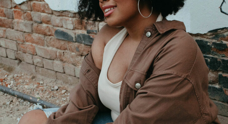 Young woman sitting and smiling in front of graffiti-stricken wall