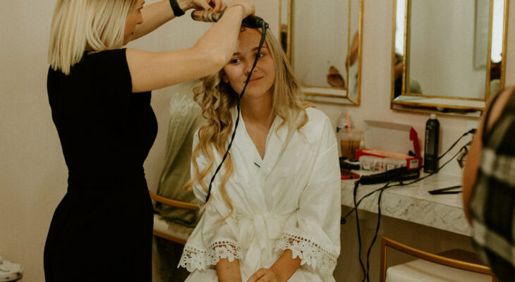 Young woman having her hair curled with curling iron at Rain Salon and Spa