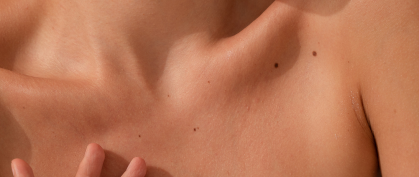 young woman with smooth, hydrated skin caresses her collar bone